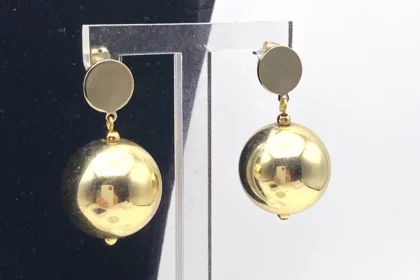 Boucles d’oreilles avec boule dorée pendante.